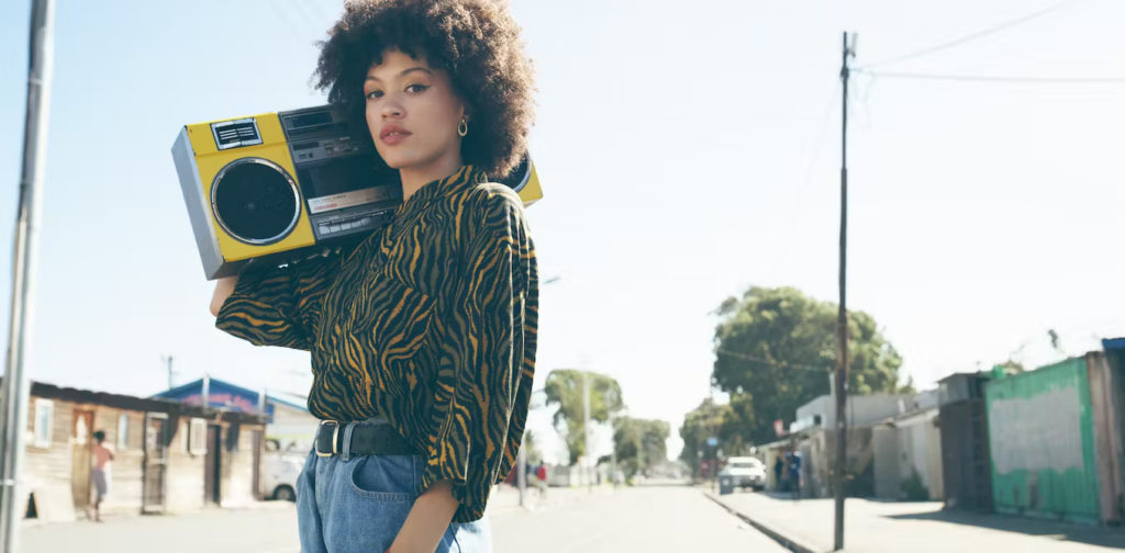 A woman holding a boombox in the street, from radio media buying agency.